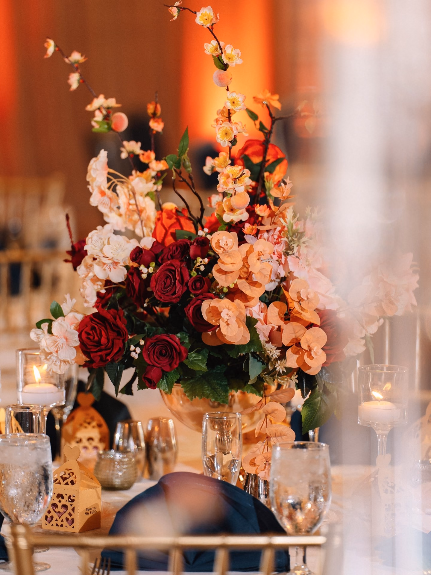 Layered florals, candlelight and glassware viewed through soft foreground detail
