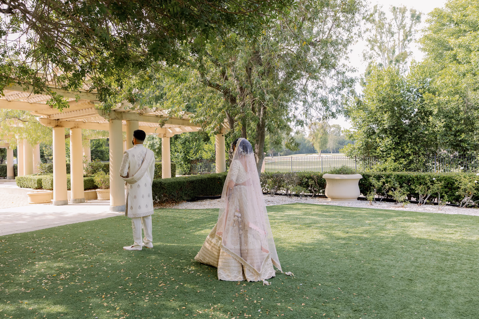 A couple anticipating their first look in a sunlit garden