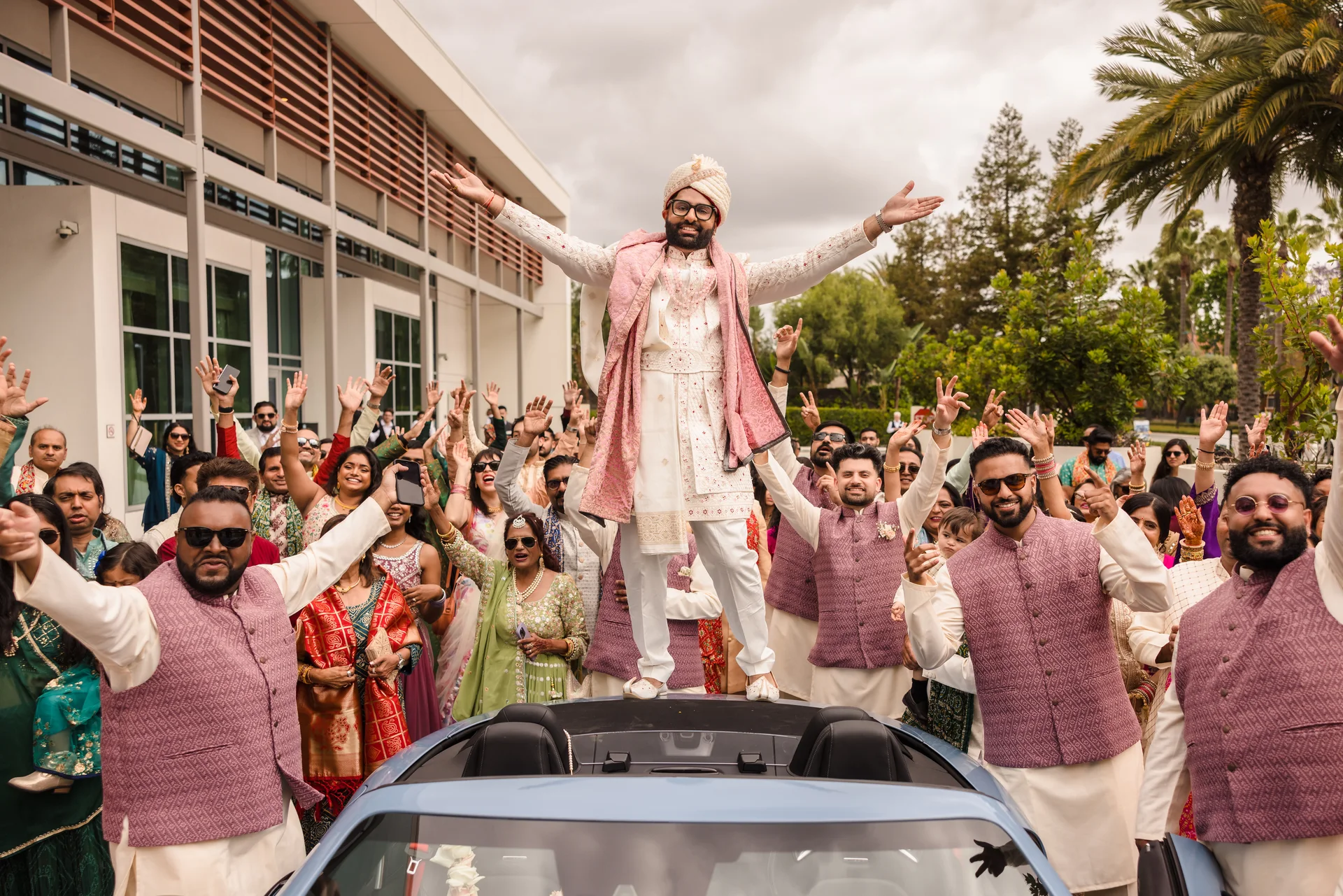 Varad and his guests celebrating around the wedding car