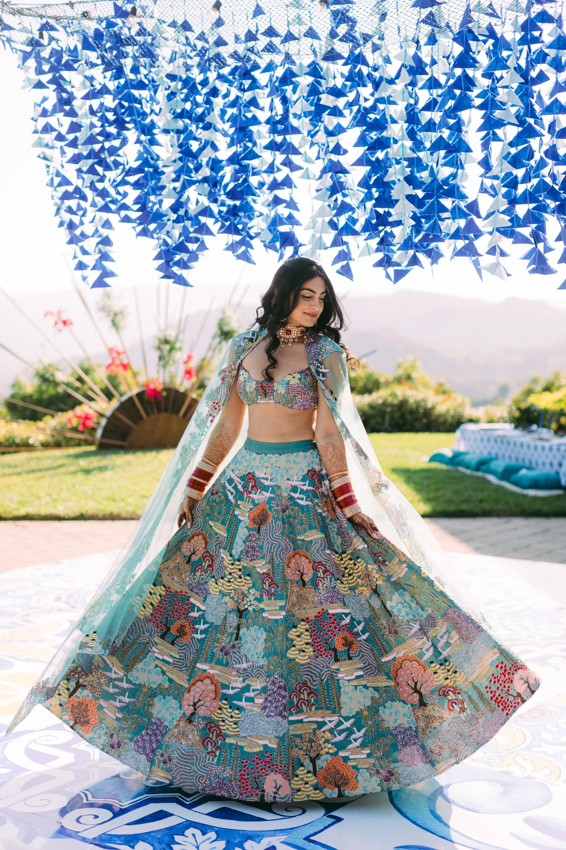 Reena beneath blue decorations in her Sangeet outfit