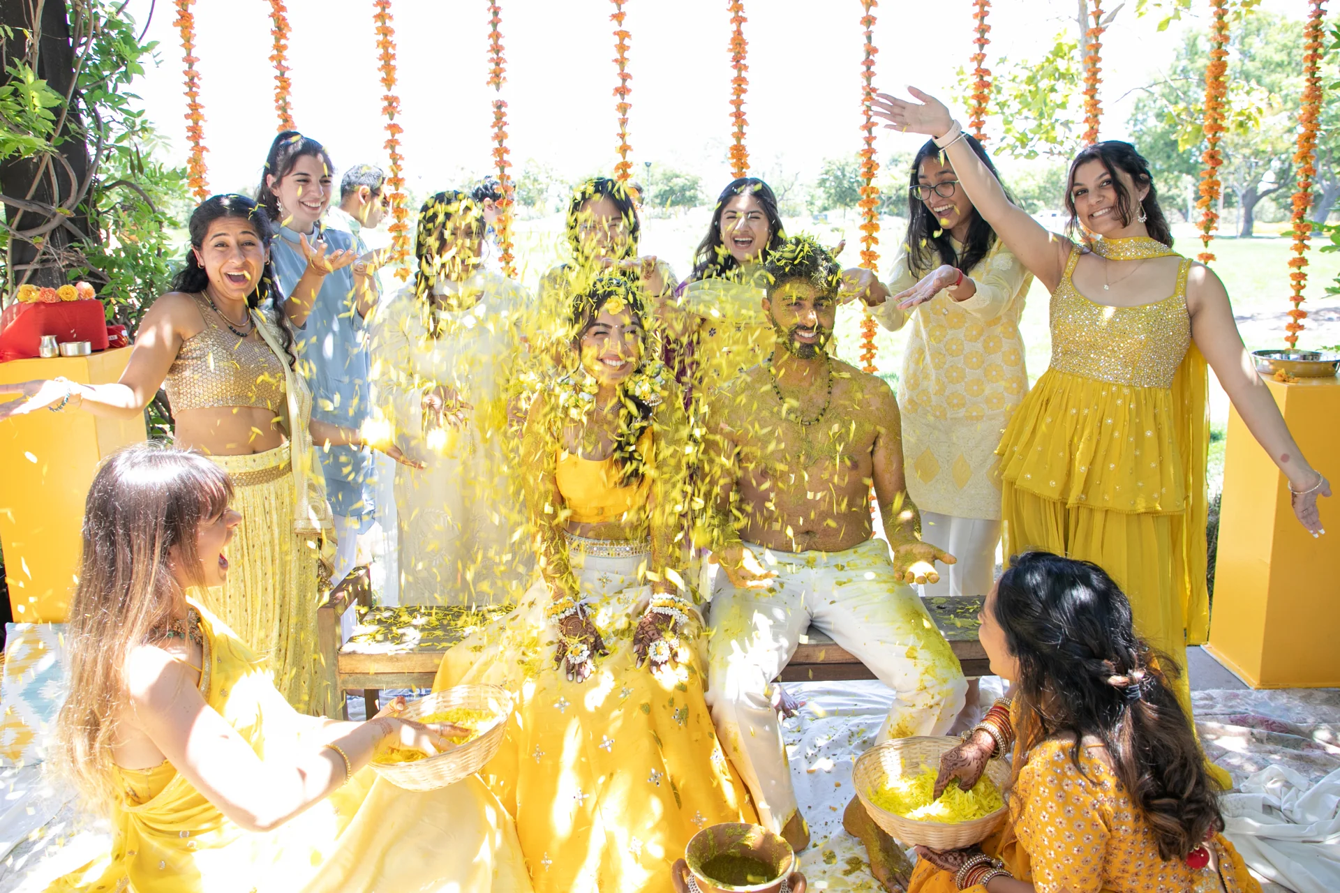 Avani and Abhi surrounded by family during a joyful yellow-toned Haldi celebration.