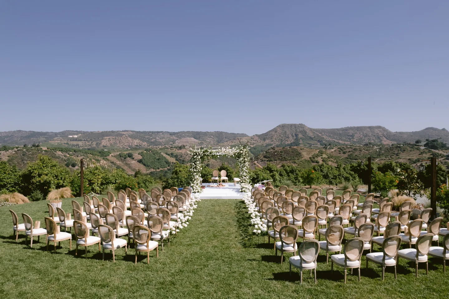An outdoor ceremony aisle and seating framed by expansive Southern California hills