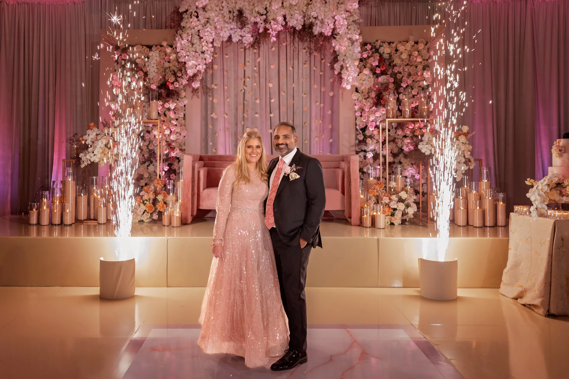 Tara and Usman surrounded by coordinated florals and reception lighting at Paséa Hotel & Spa.