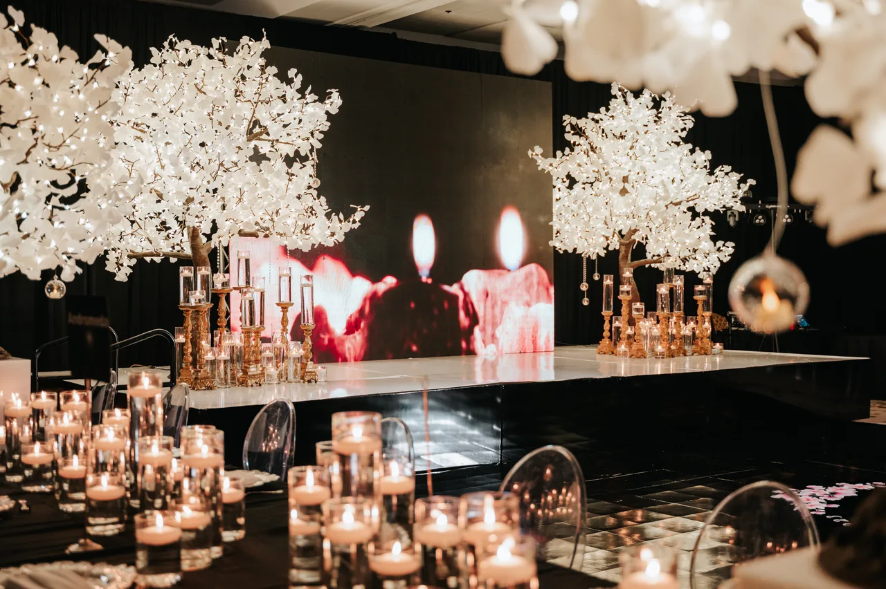 Candlelit reception tables opening onto the dance floor, framed by illuminated floral trees