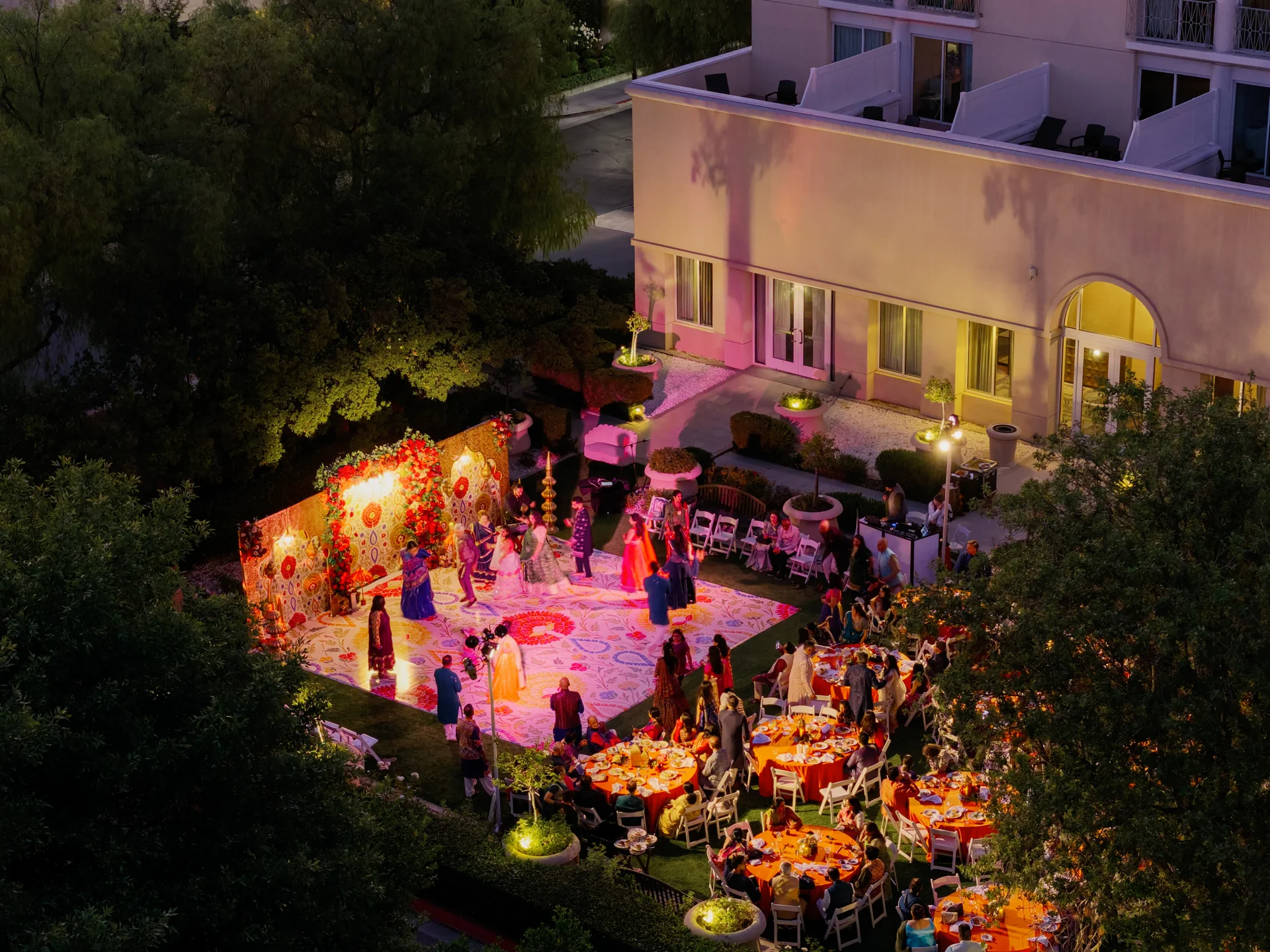 Guests gathered around a brightly lit outdoor Sangeet at dusk for Mahima and Sarang.