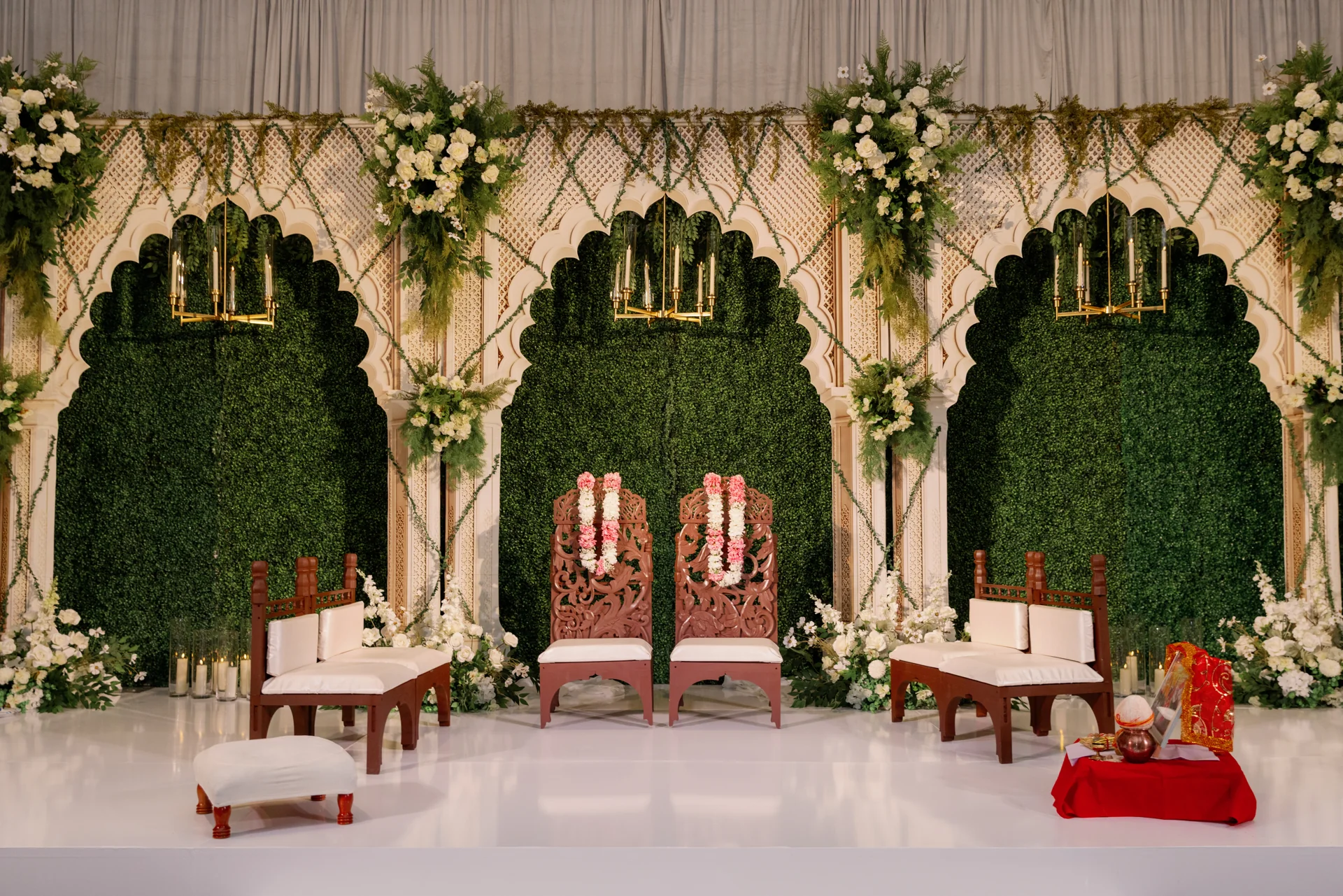 Mahima and Sarang’s Indian ceremony setting with floral garlands and carved chairs