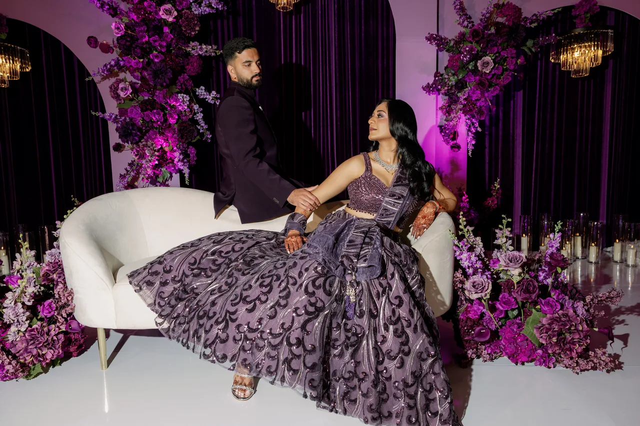 Mahima and Sarang together within their purple floral reception setting